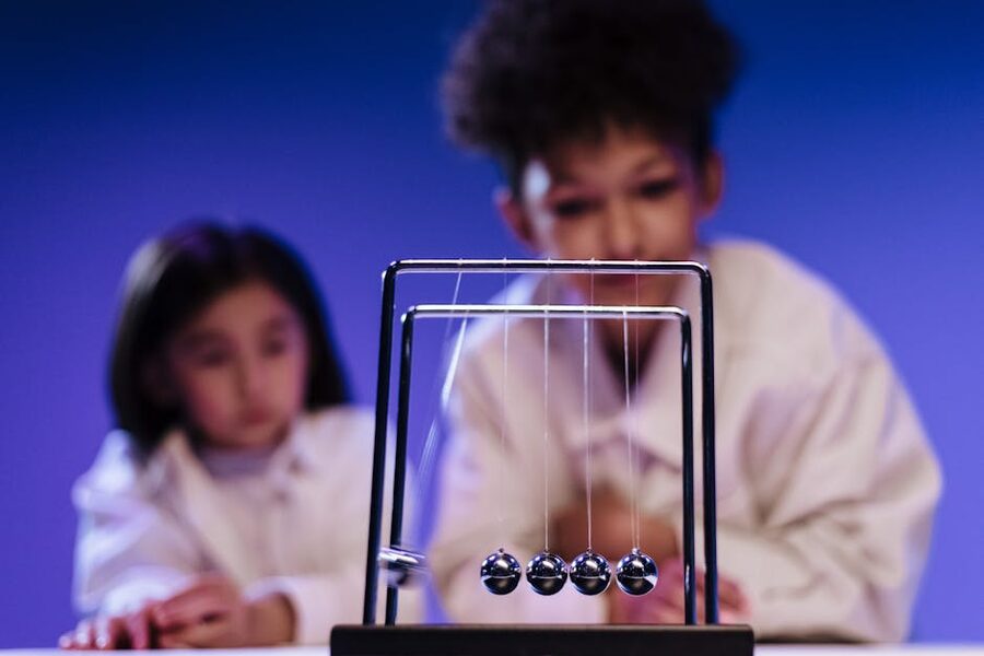 Children watching a Newtons cradle science exhibit
