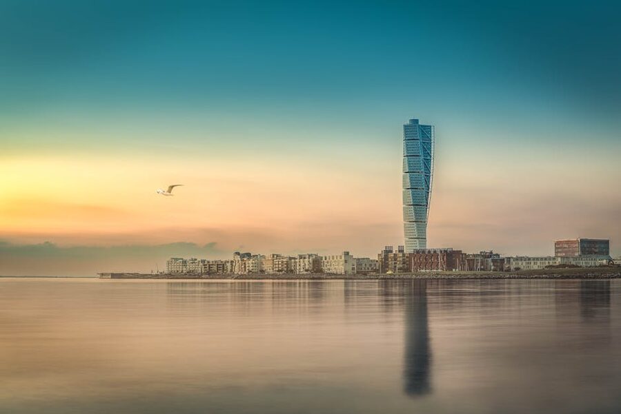 Turning Torso reflecting on Malmö waterfront at sunset