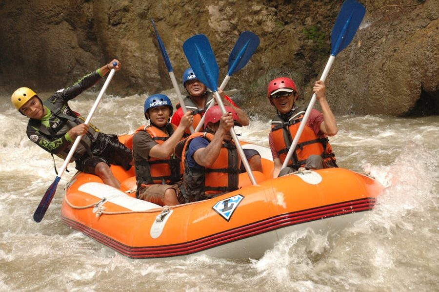 Group of adults whitewater rafting in turbulent rapids
