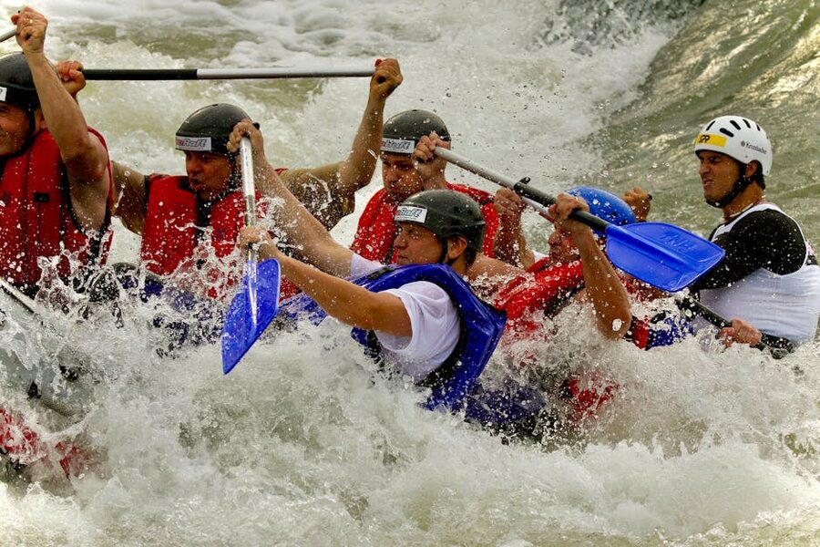 Rafters in helmets navigating whitewater rapids