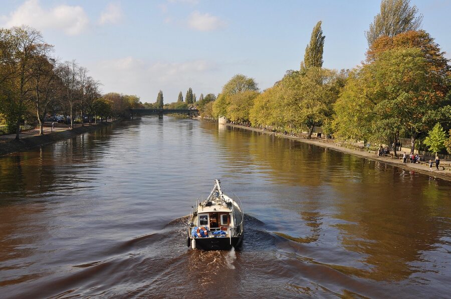 A York river cruise boat moving along the River Ouse on a sunny day